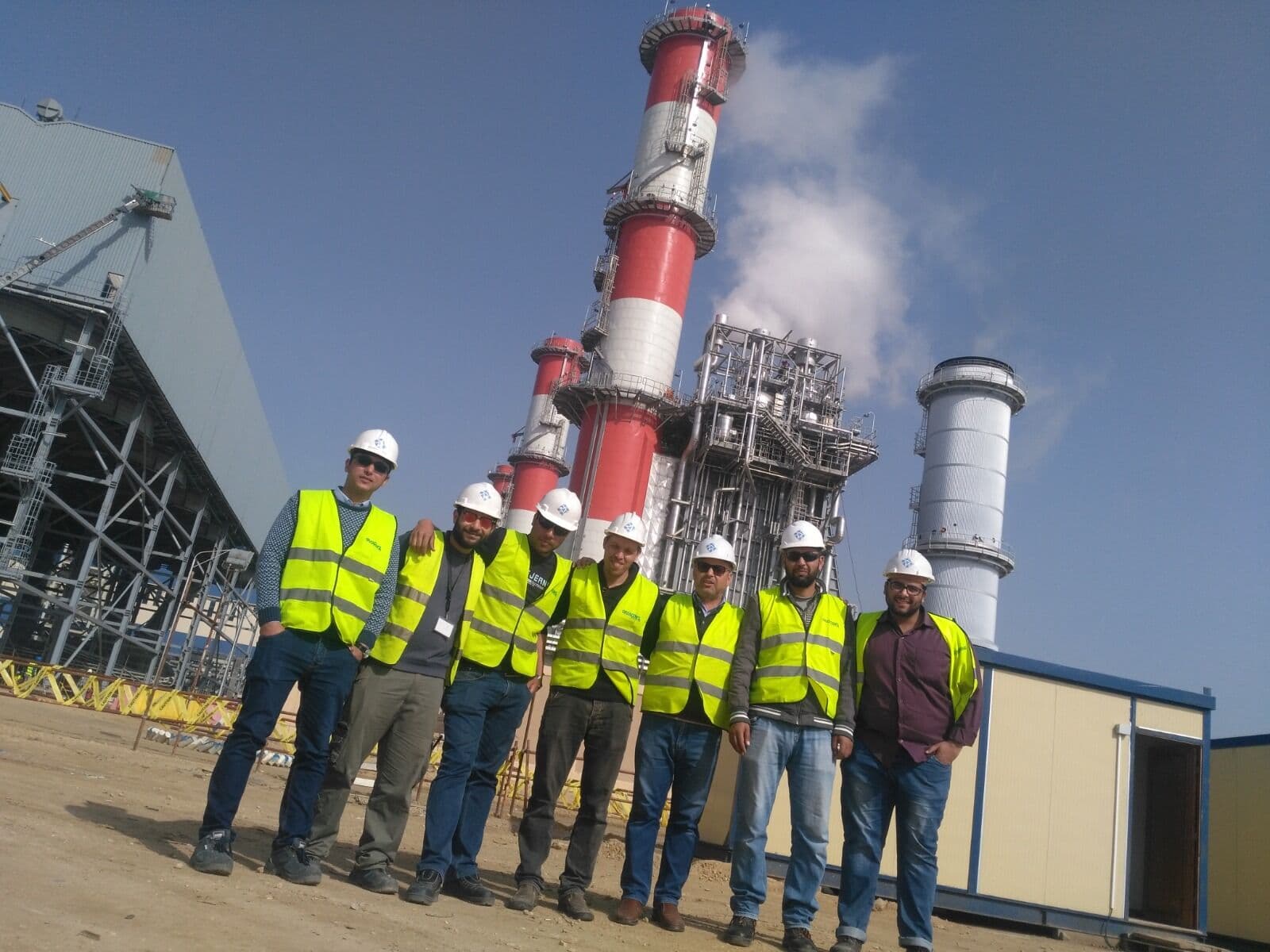 PAT commissioning team on site in front of the plant stacks